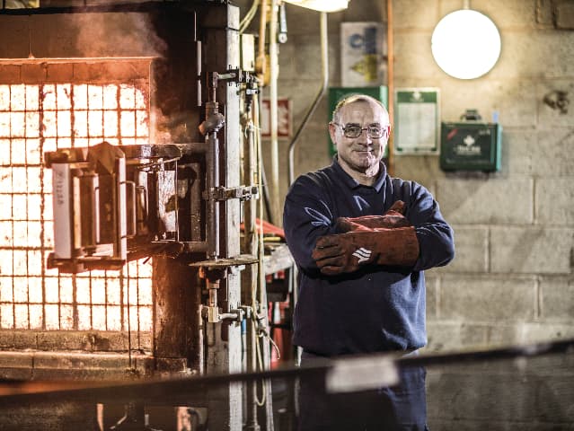 Element fire and flammability testing engineer standing in front of test frame glowing from high-temperature fire testing